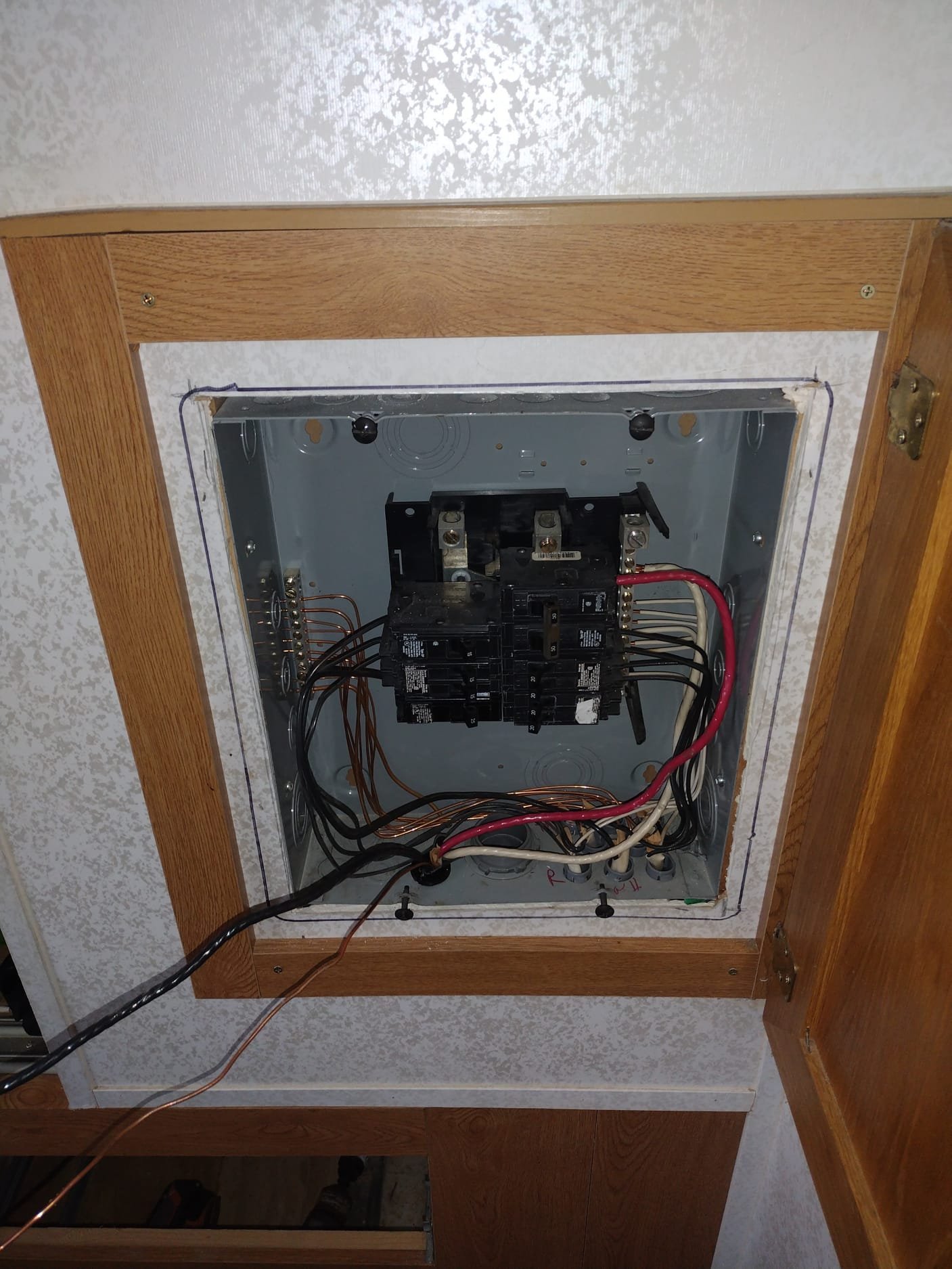 New electrical panel installed in a wooden cabinet, showcasing a modern, safe setup