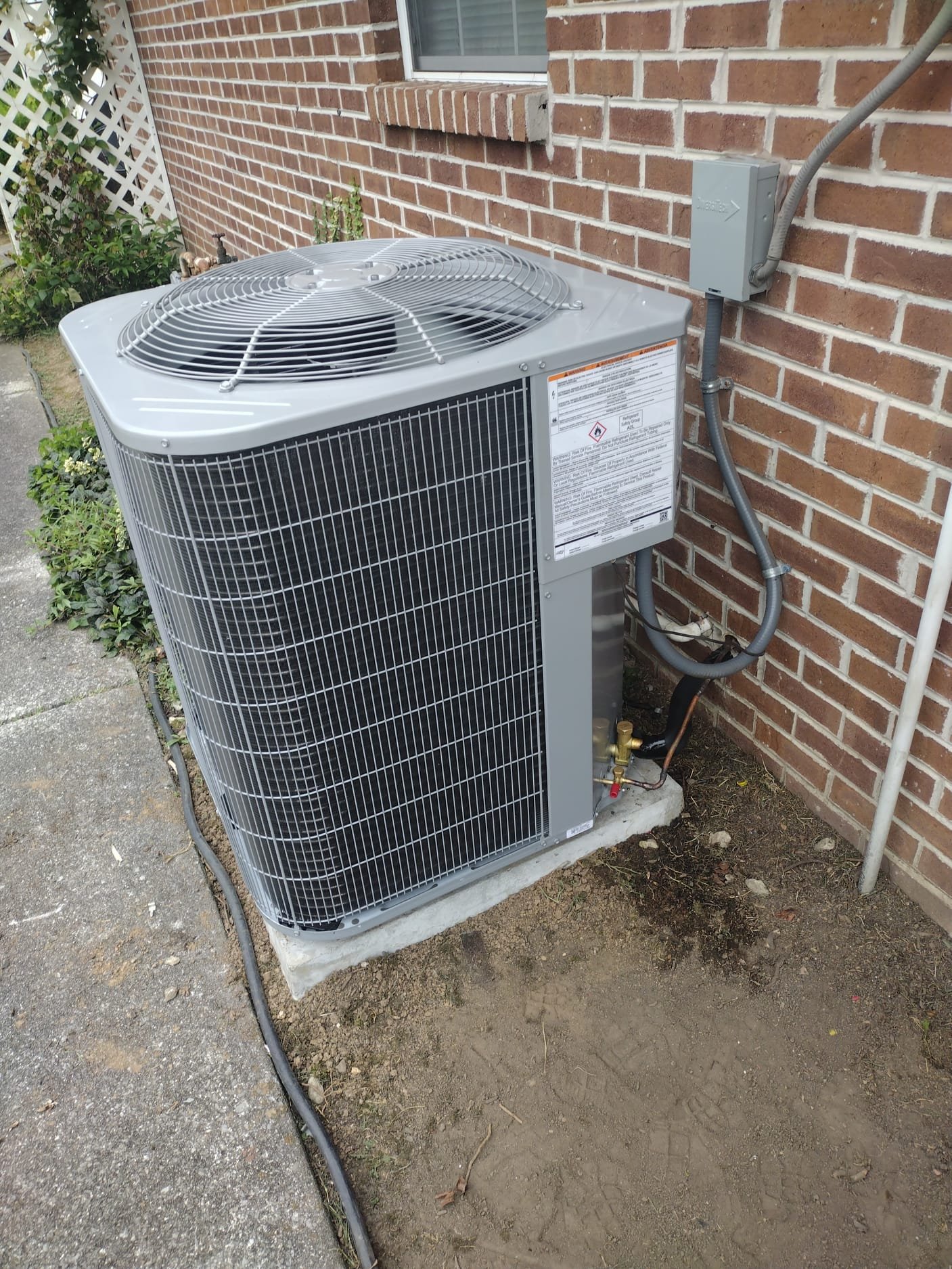 New outdoor HVAC unit installed next to a brick wall, showcasing modern design