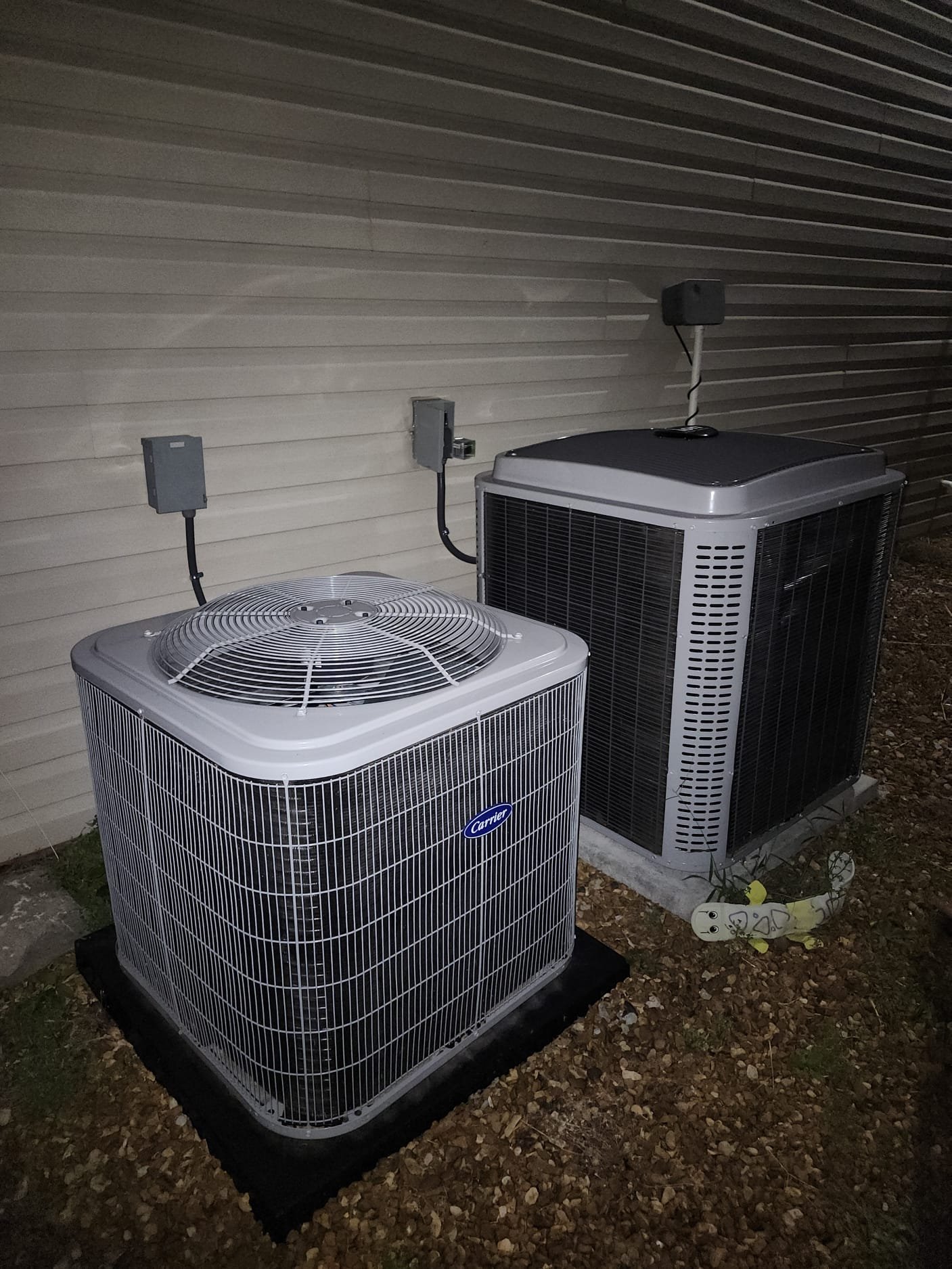 A newly installed outdoor condenser unit next to an older model