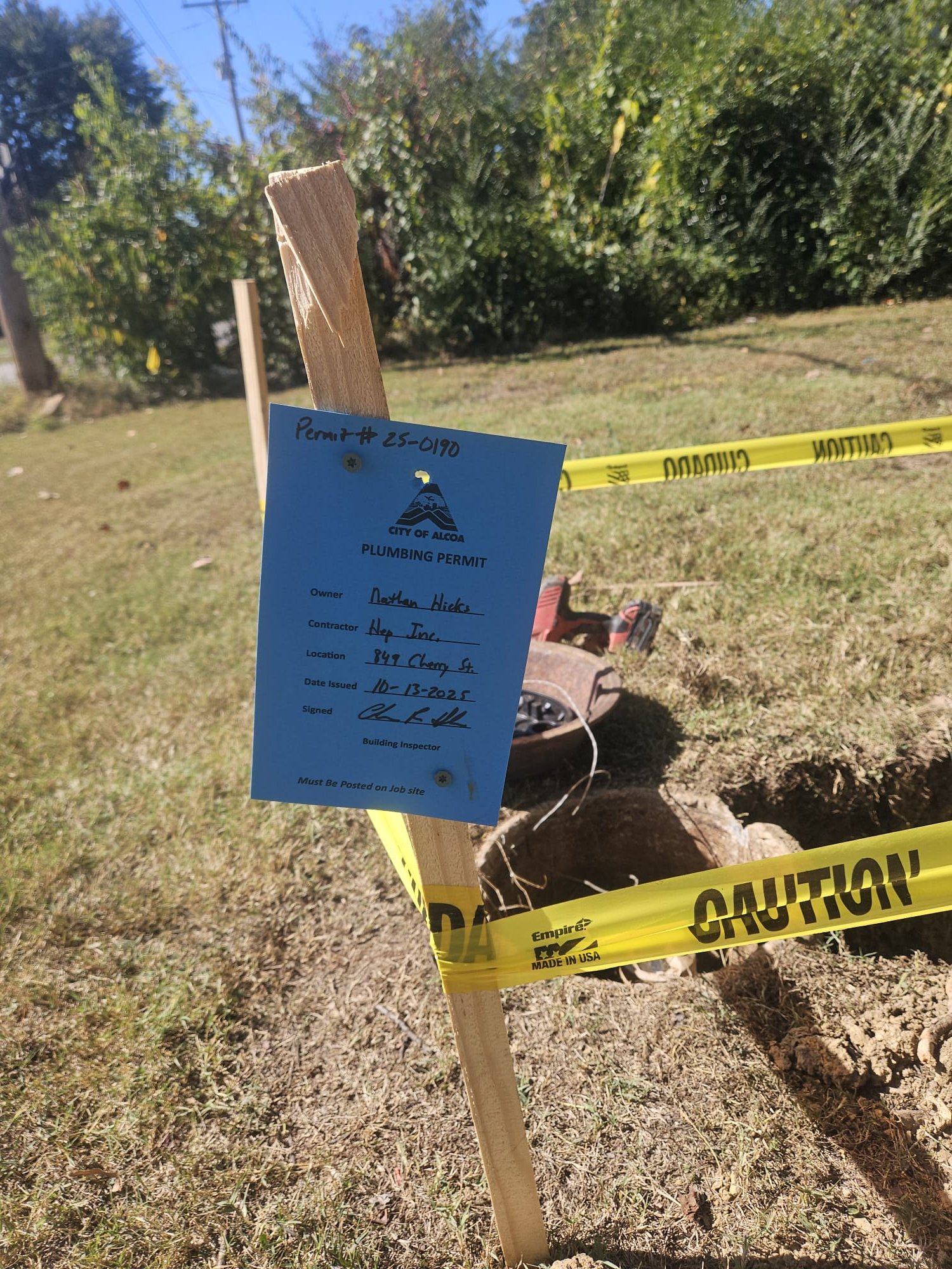 City permit posted next to a freshly dug hole and caution tape