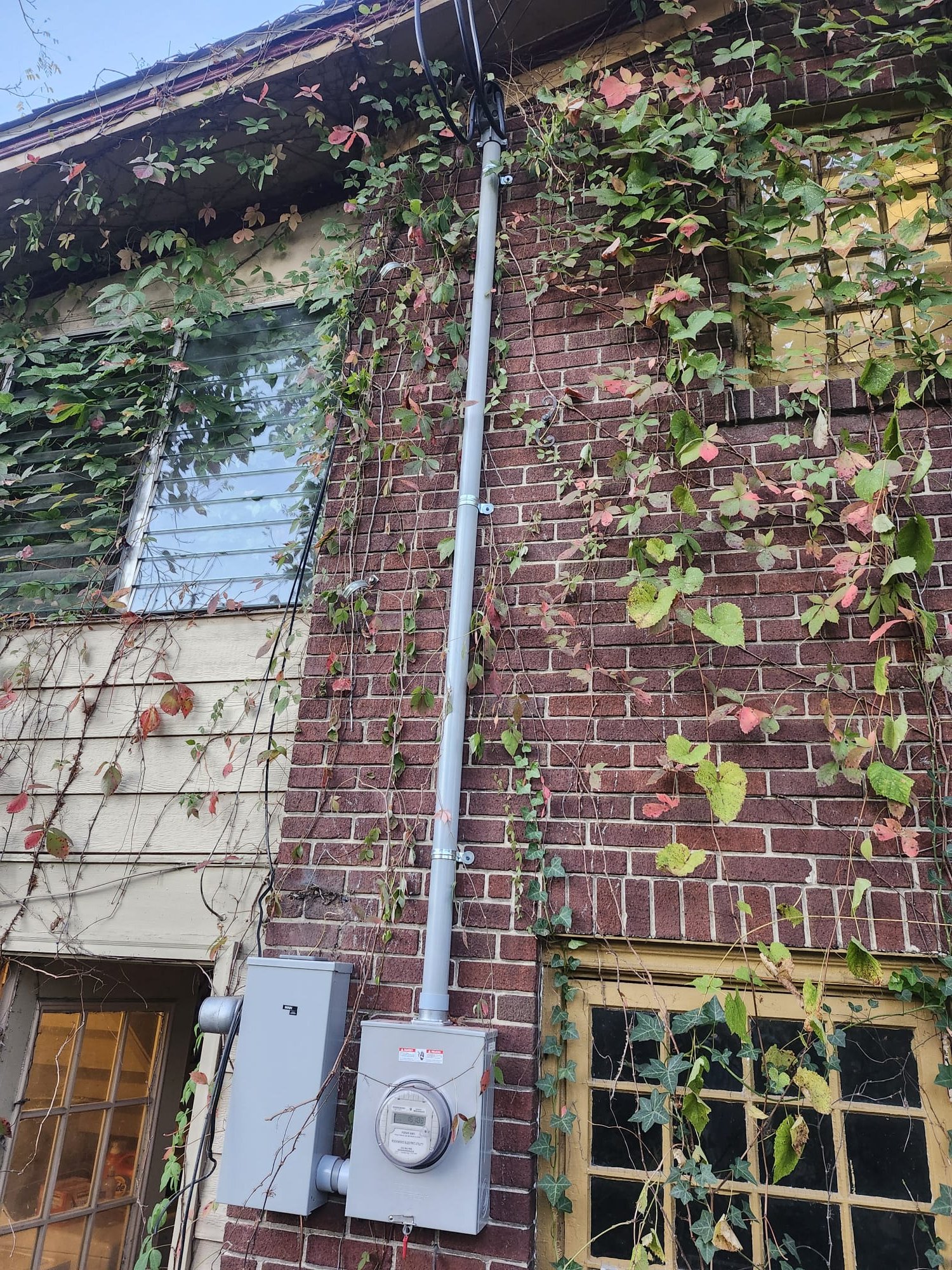 New meter base and service conduit installed on a brick wall