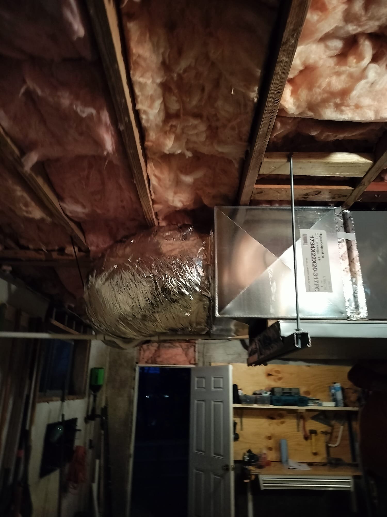 Shiny new sheet-metal ductwork suspended in a basement utility area