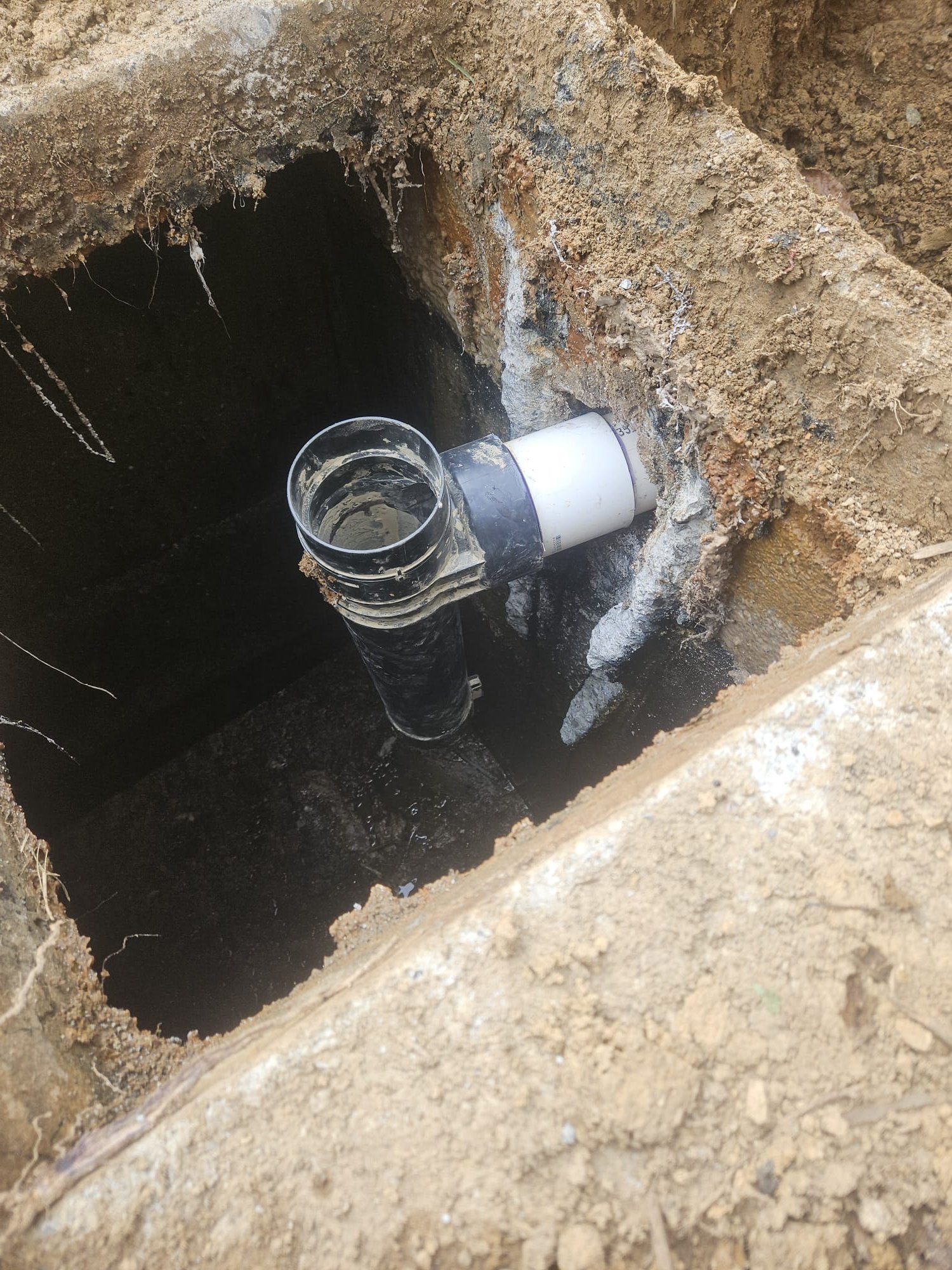 Freshly installed pipe through a foundation wall, ready for backfill