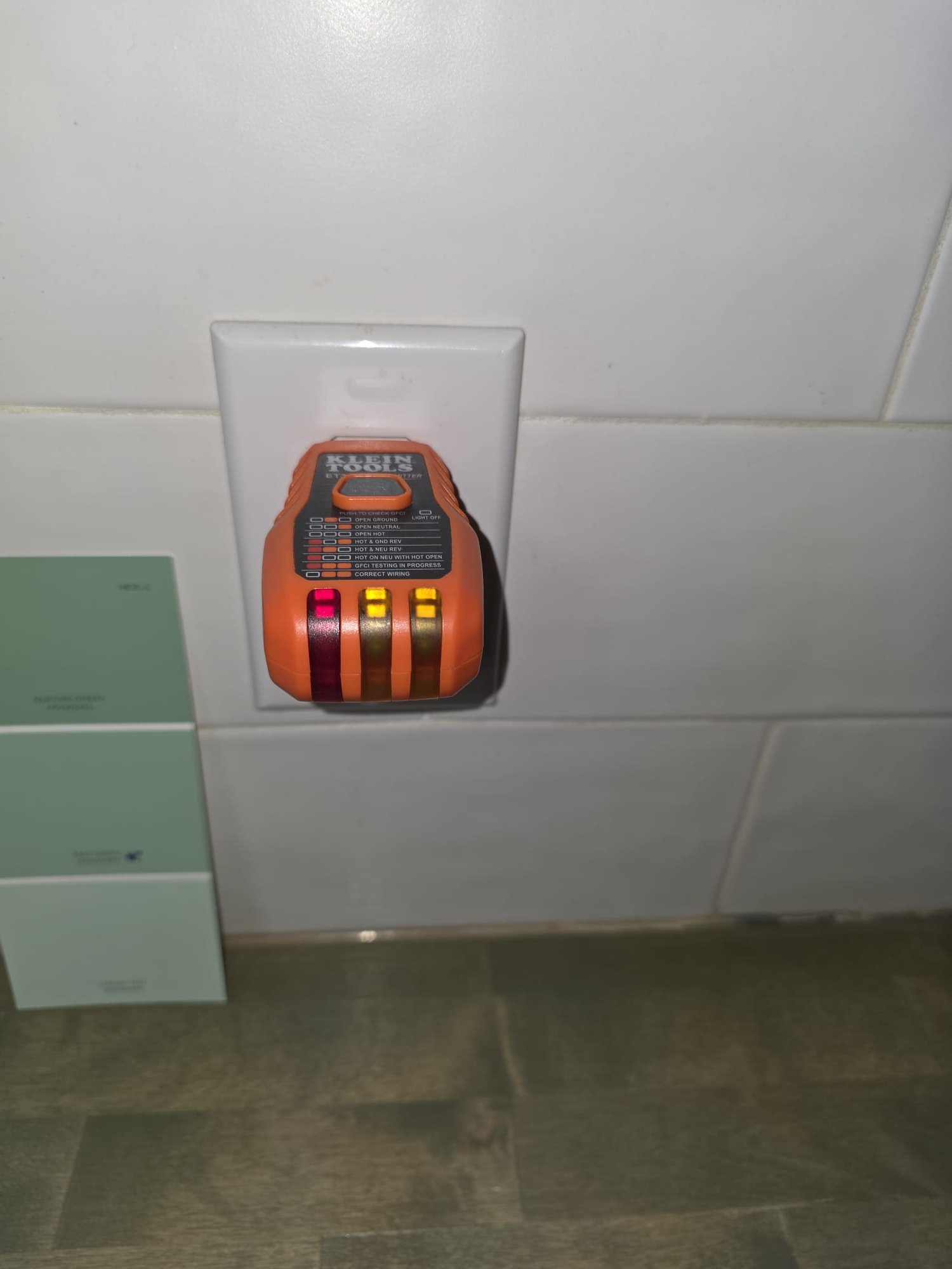 This image shows an outlet tester plugged into a kitchen receptacle, verifying correct wiring and power delivery.