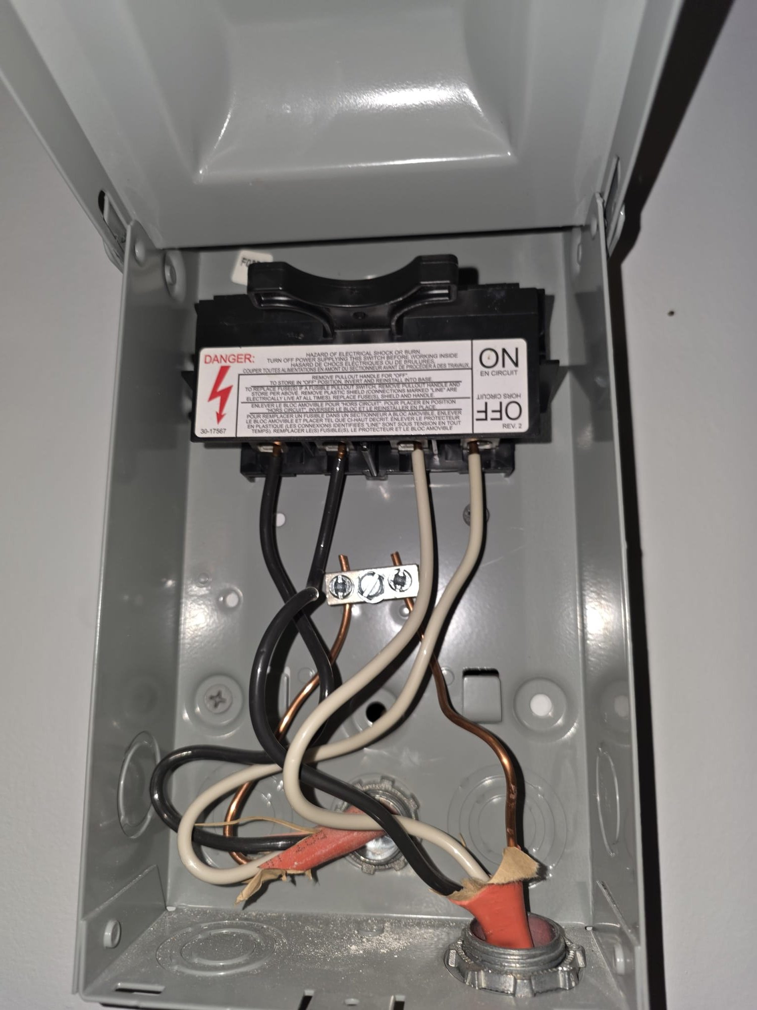 This image shows the inside of a newly installed electrical disconnect box, with clean wiring and a properly secured breaker switch.