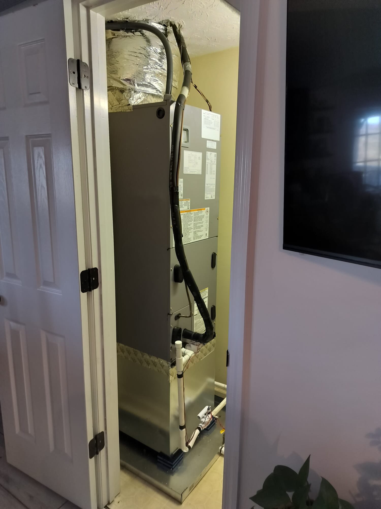 Newly installed indoor air handler unit in a utility closet with fresh insulation
