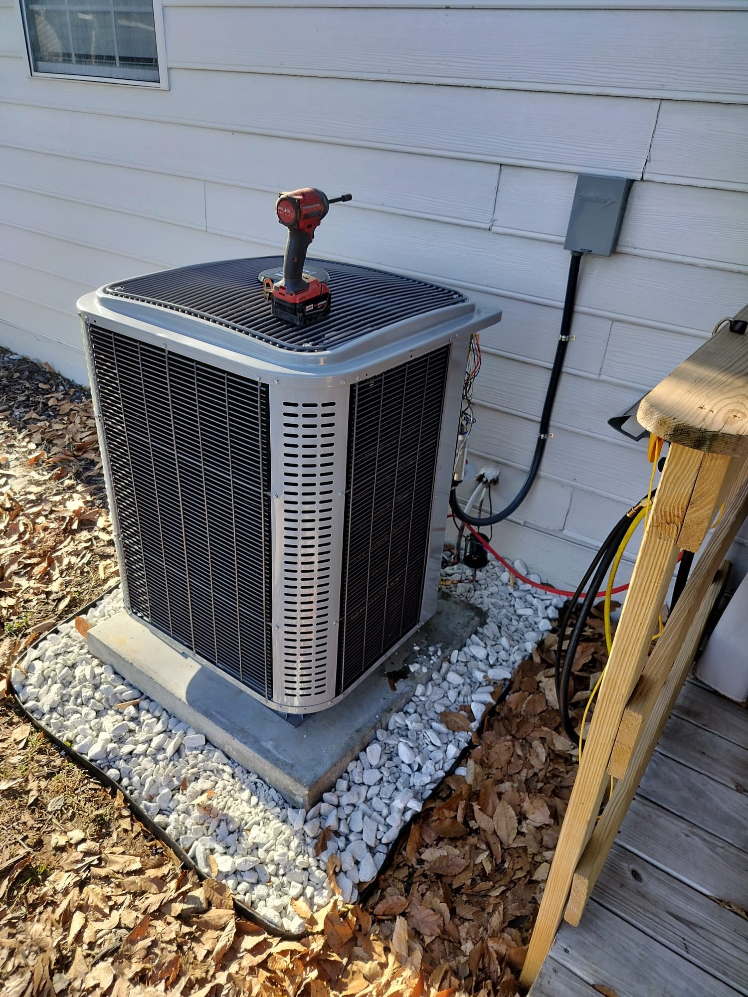 Outdoor unit with open access panel and neatly routed electrical lines next to the disconnect box