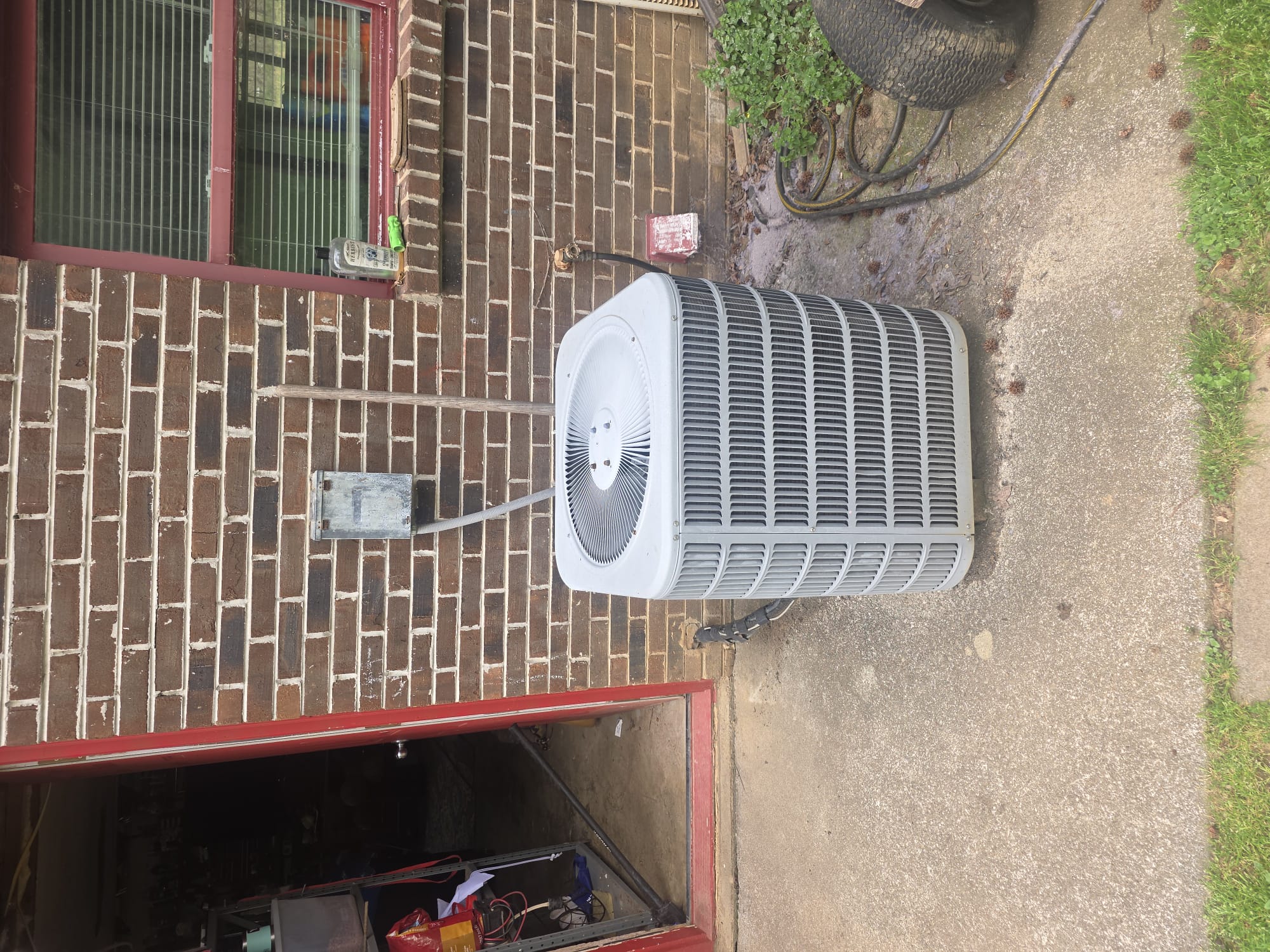 New outdoor HVAC condenser unit next to a brick wall
