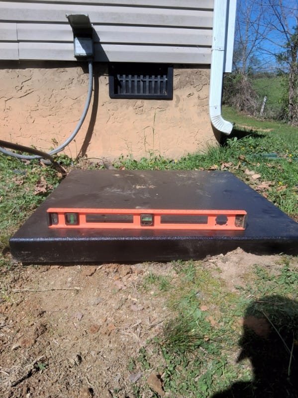 Level tool checking a new HVAC pad installation