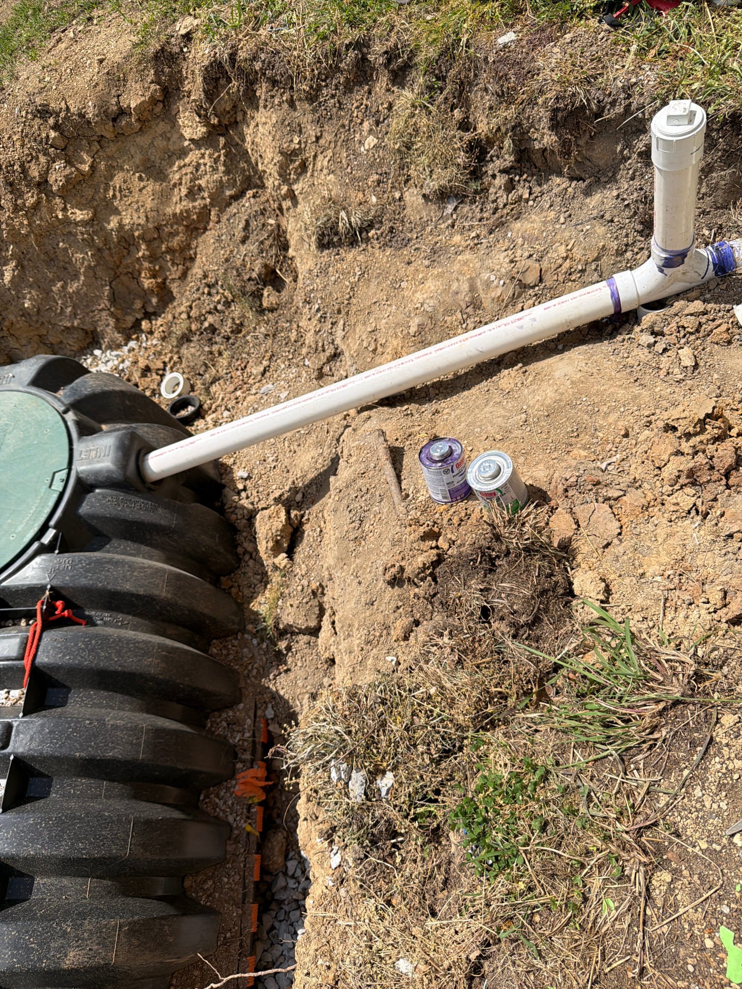 Large black septic tank with primer and PVC cement visible
