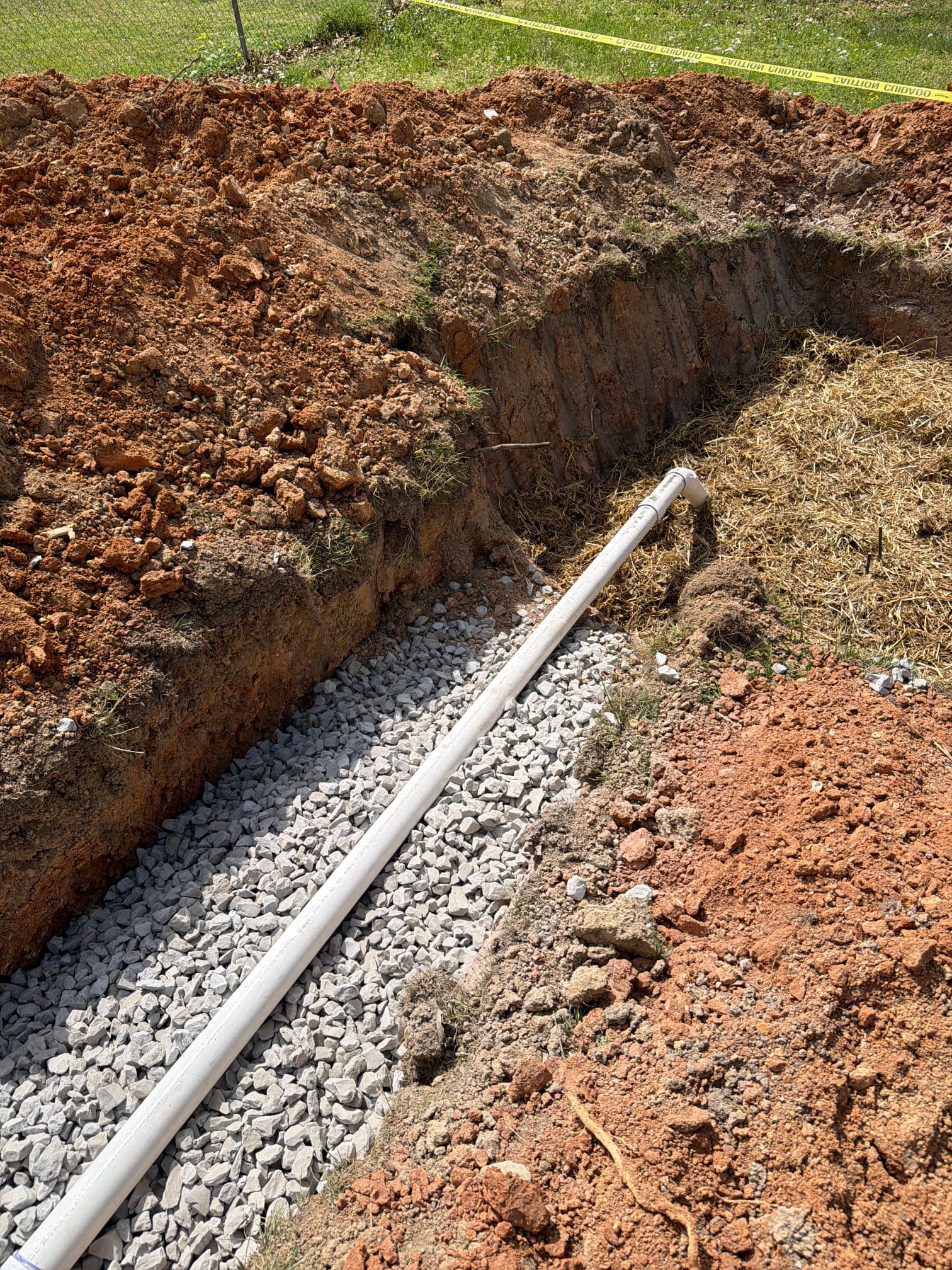 Trench with new PVC pipe laid on gravel bed