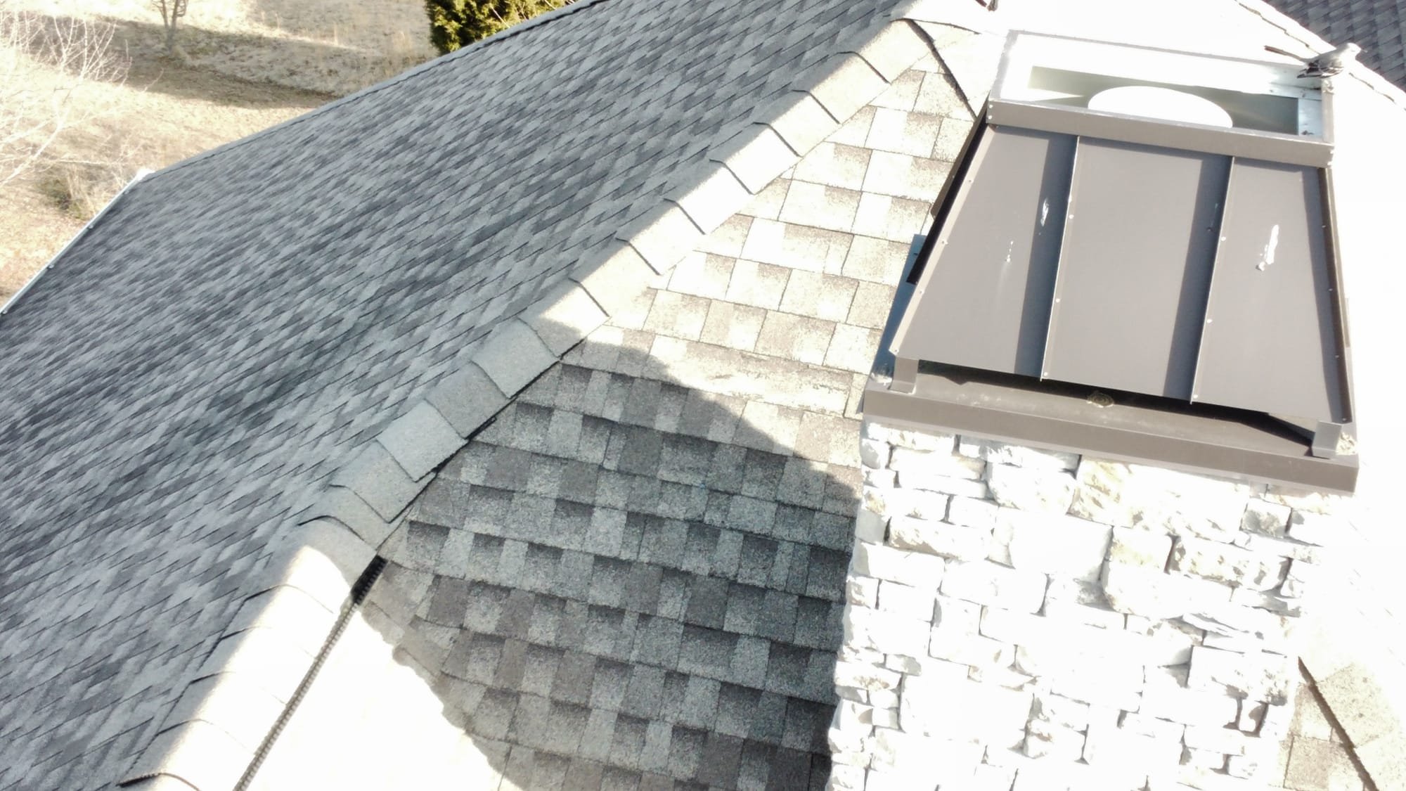 Newly installed asphalt shingles and chimney cap.