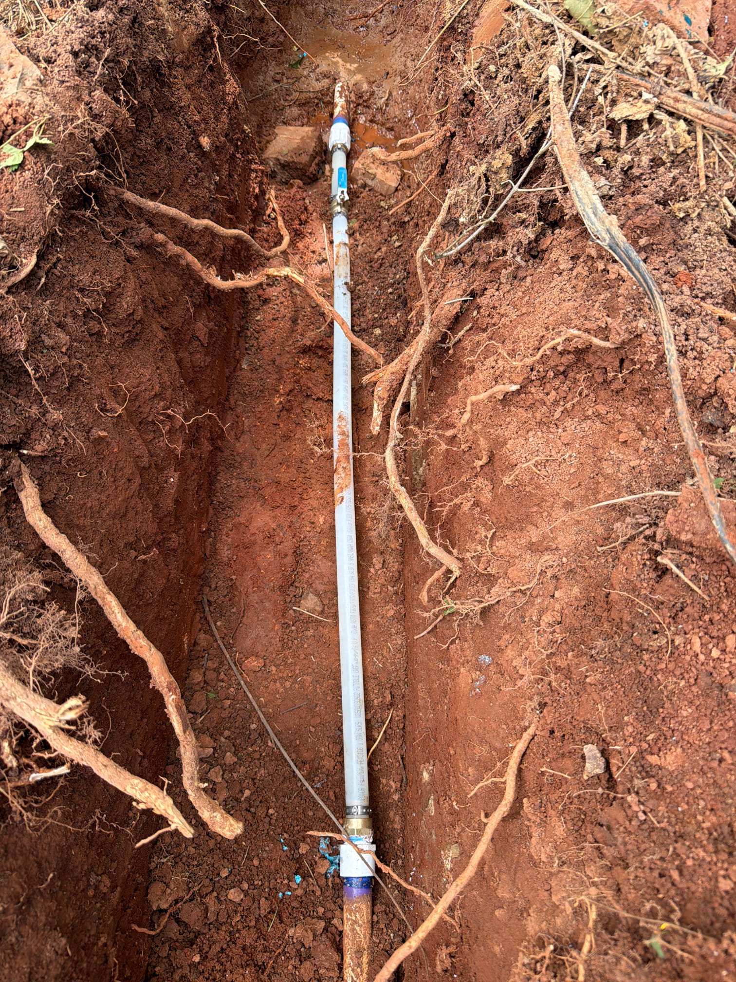 Section of underground pipe replaced with new flexible piping and secured with metal clamps