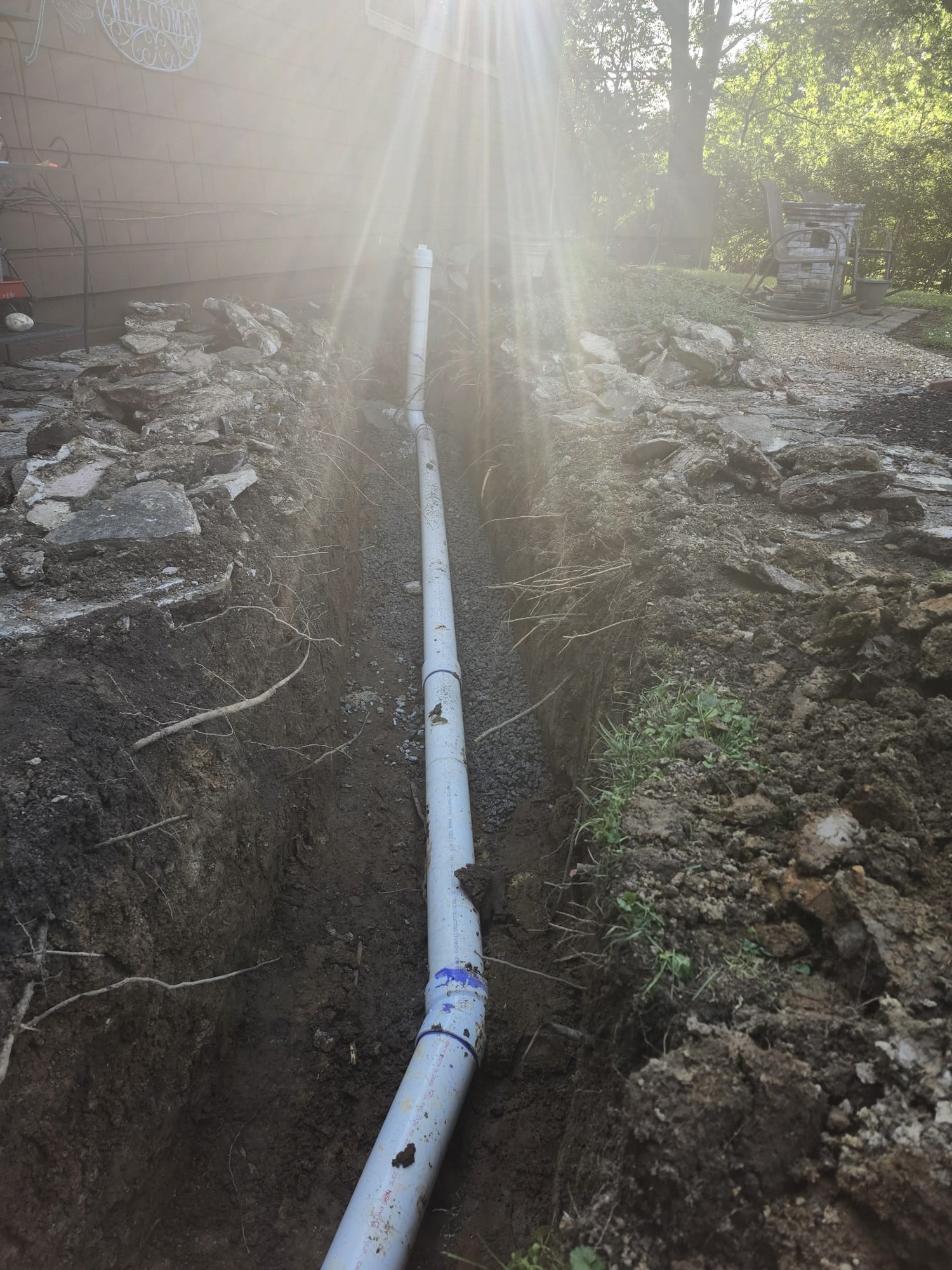 Newly installed PVC pipe set on a gravel bed in a freshly dug trench