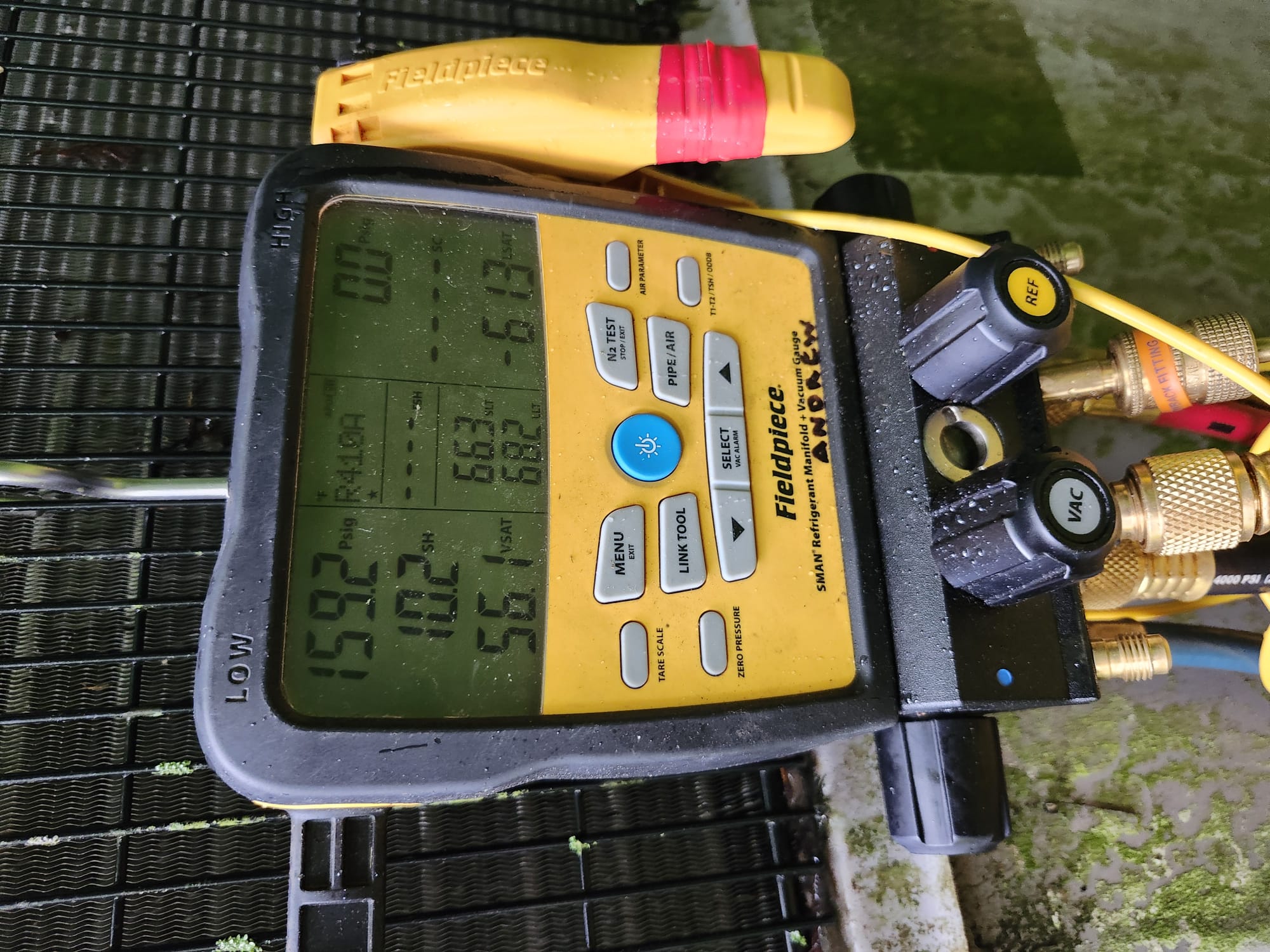 Technician using a digital manifold gauge to check refrigerant pressures.