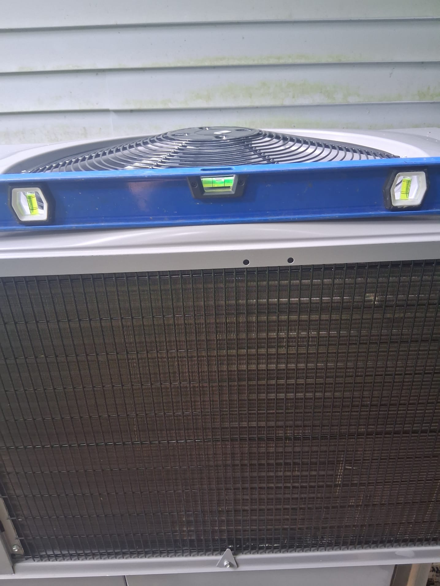 Level tool placed on top of the condenser to confirm proper installation.