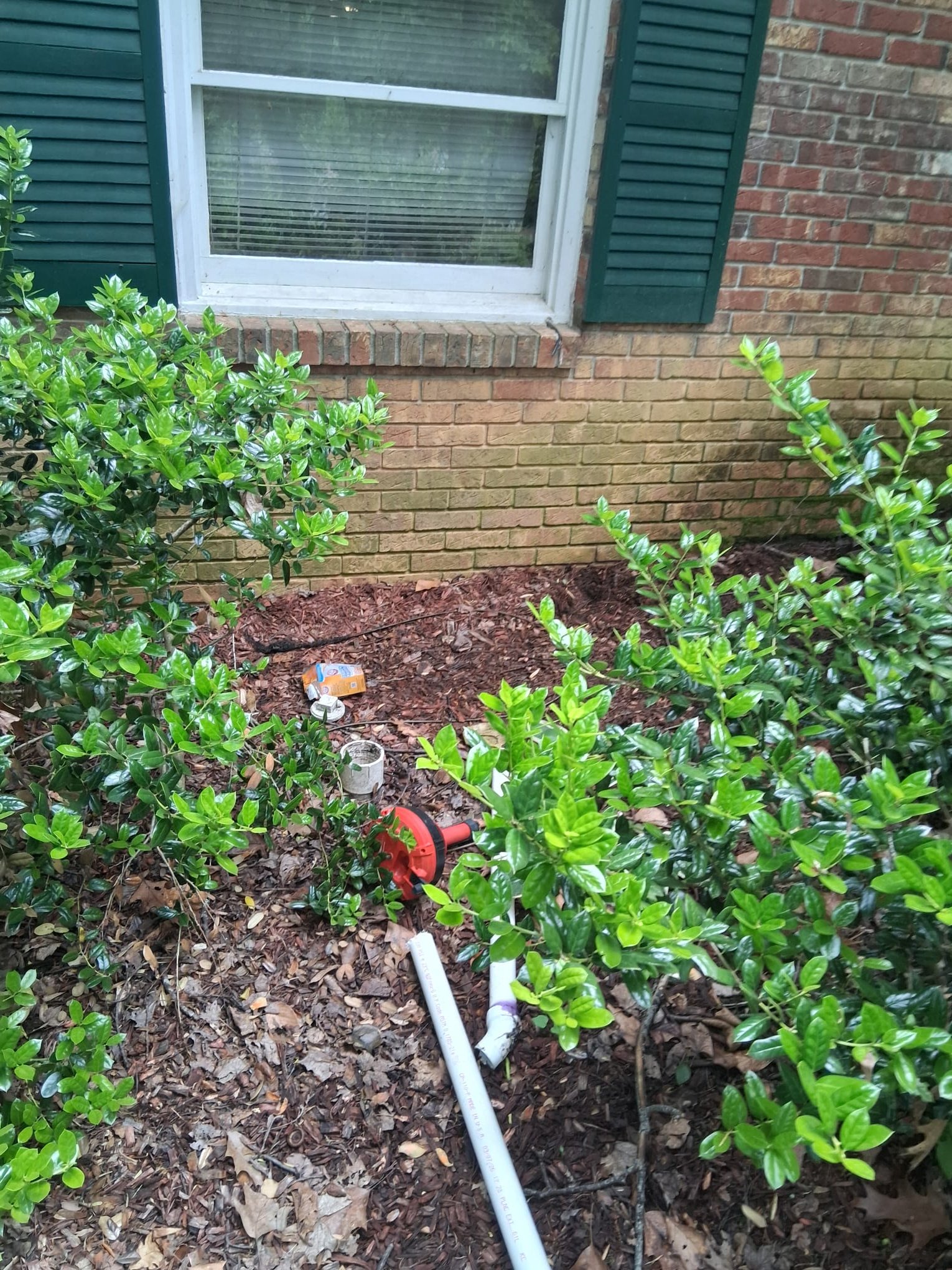 A new PVC drain line is being positioned before backfilling and concrete repair.