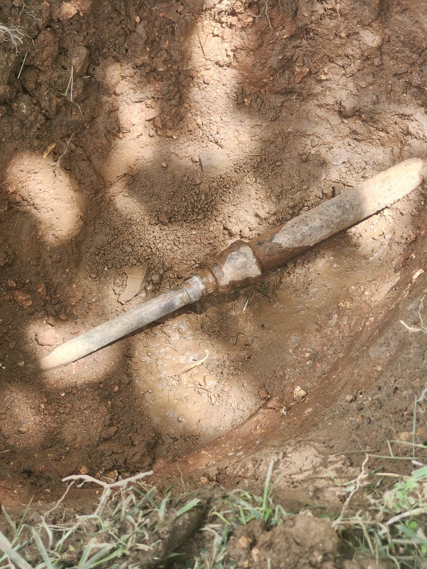 Another view of an exposed old pipe in wet soil before repair