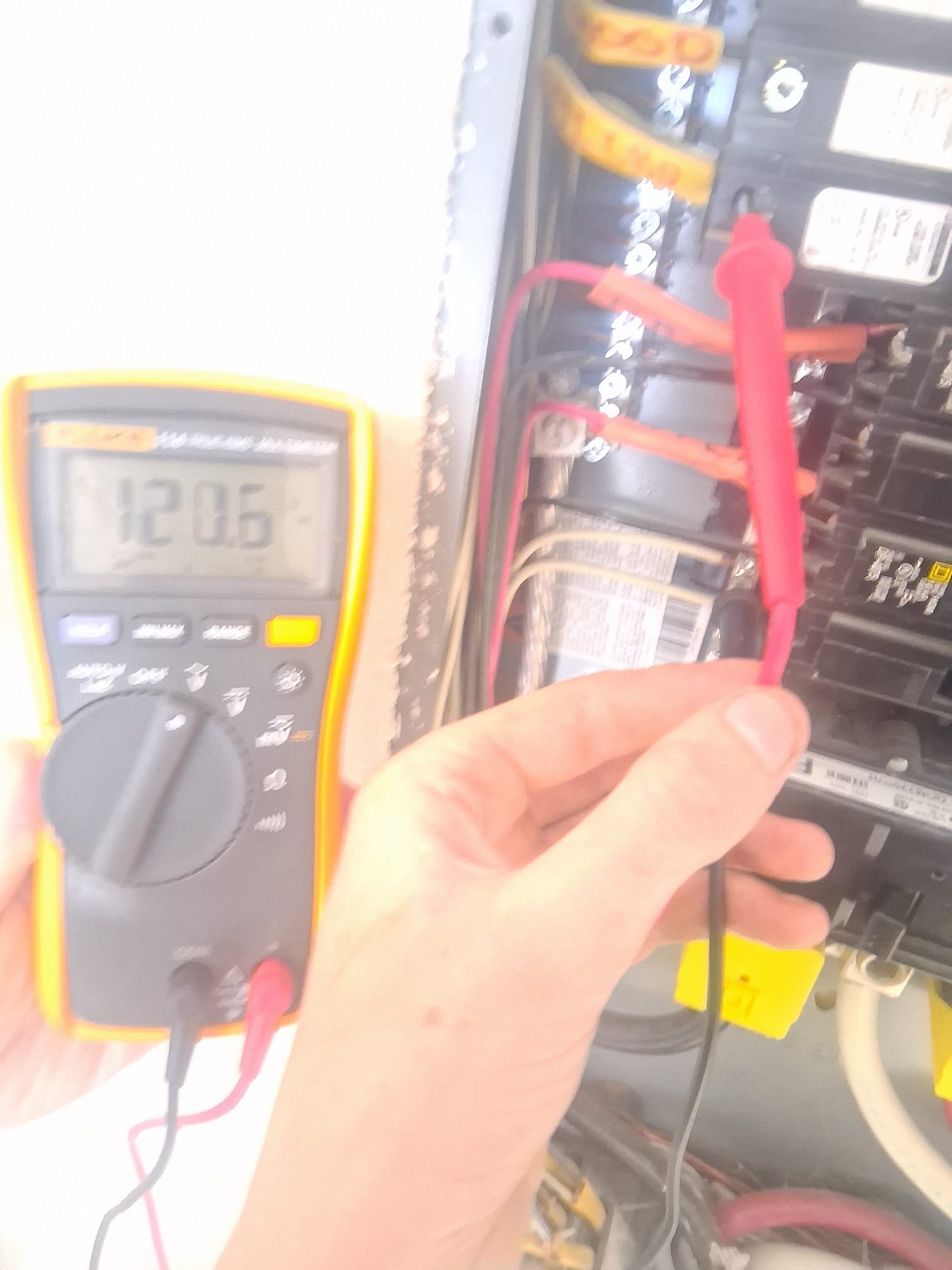 HEP technician testing voltage at an open service panel