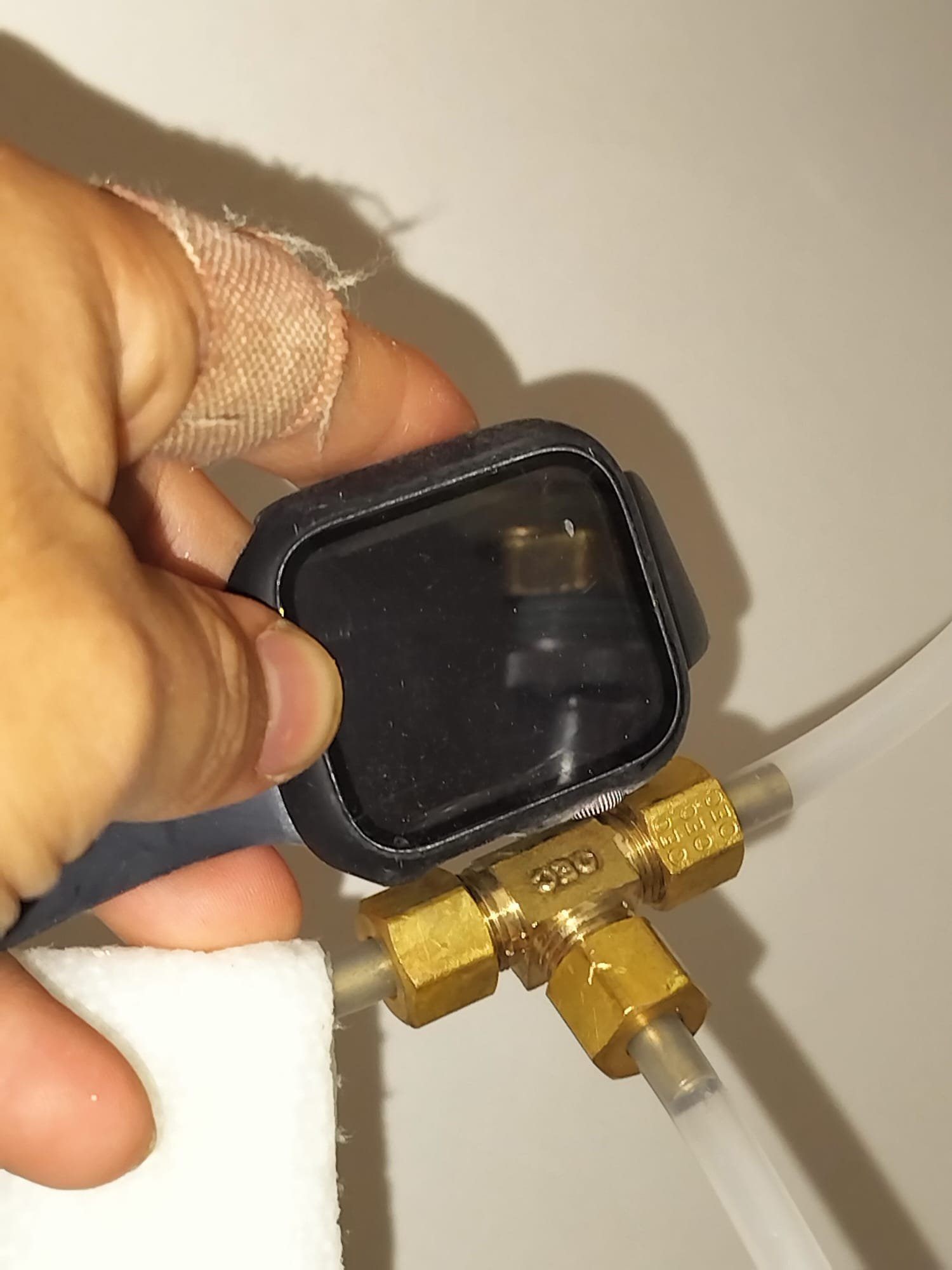 Close-up of a small brass fitting and flexible tubing being inspected for leaks