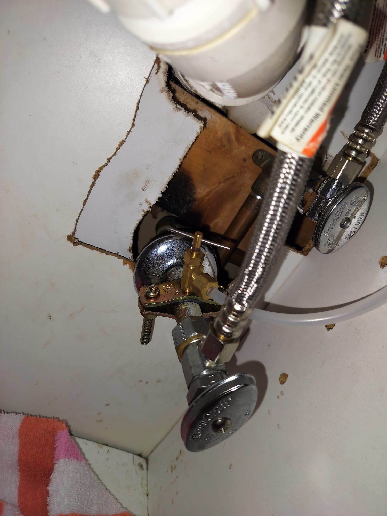 Shiny shutoff valves and braided supply lines arranged neatly inside a cabinet