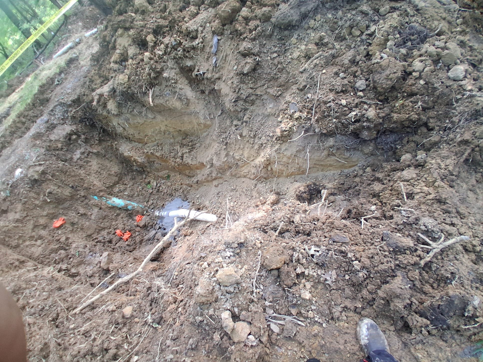 Open trench showing exposed underground plumbing during repair work