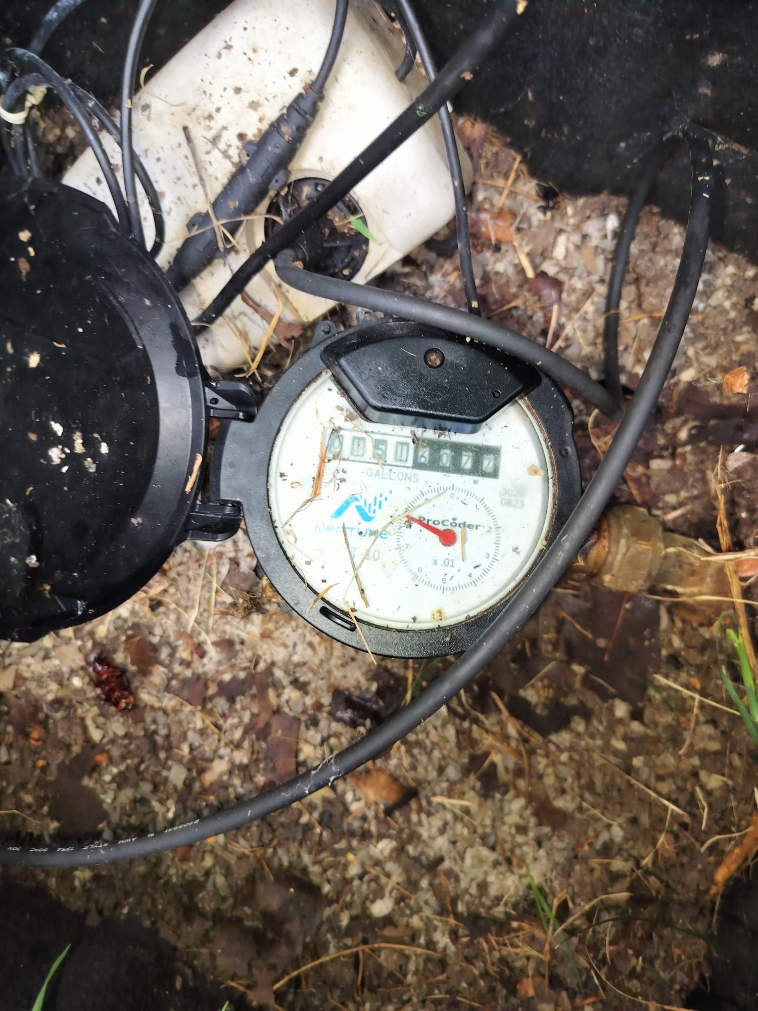 An outdoor water meter and surrounding box area showing an older, weathered setup