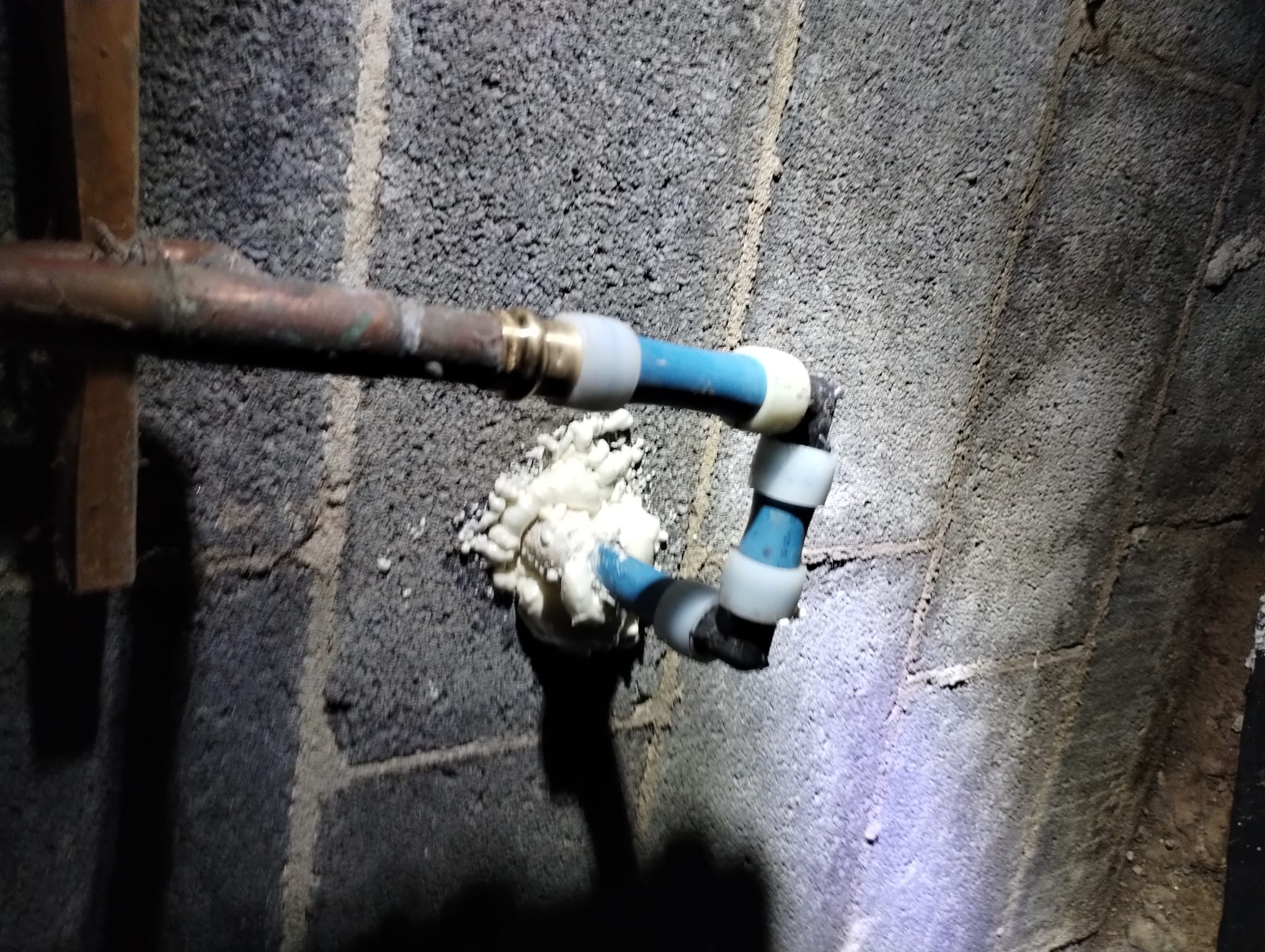 A newly installed copper and PEX plumbing connection in a crawl space