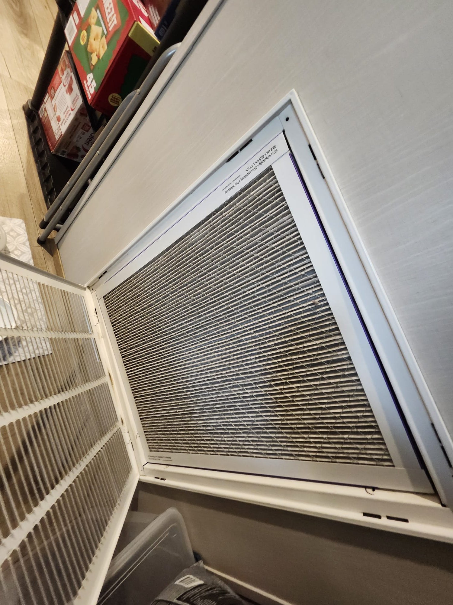 A used HVAC air filter behind an open return grille