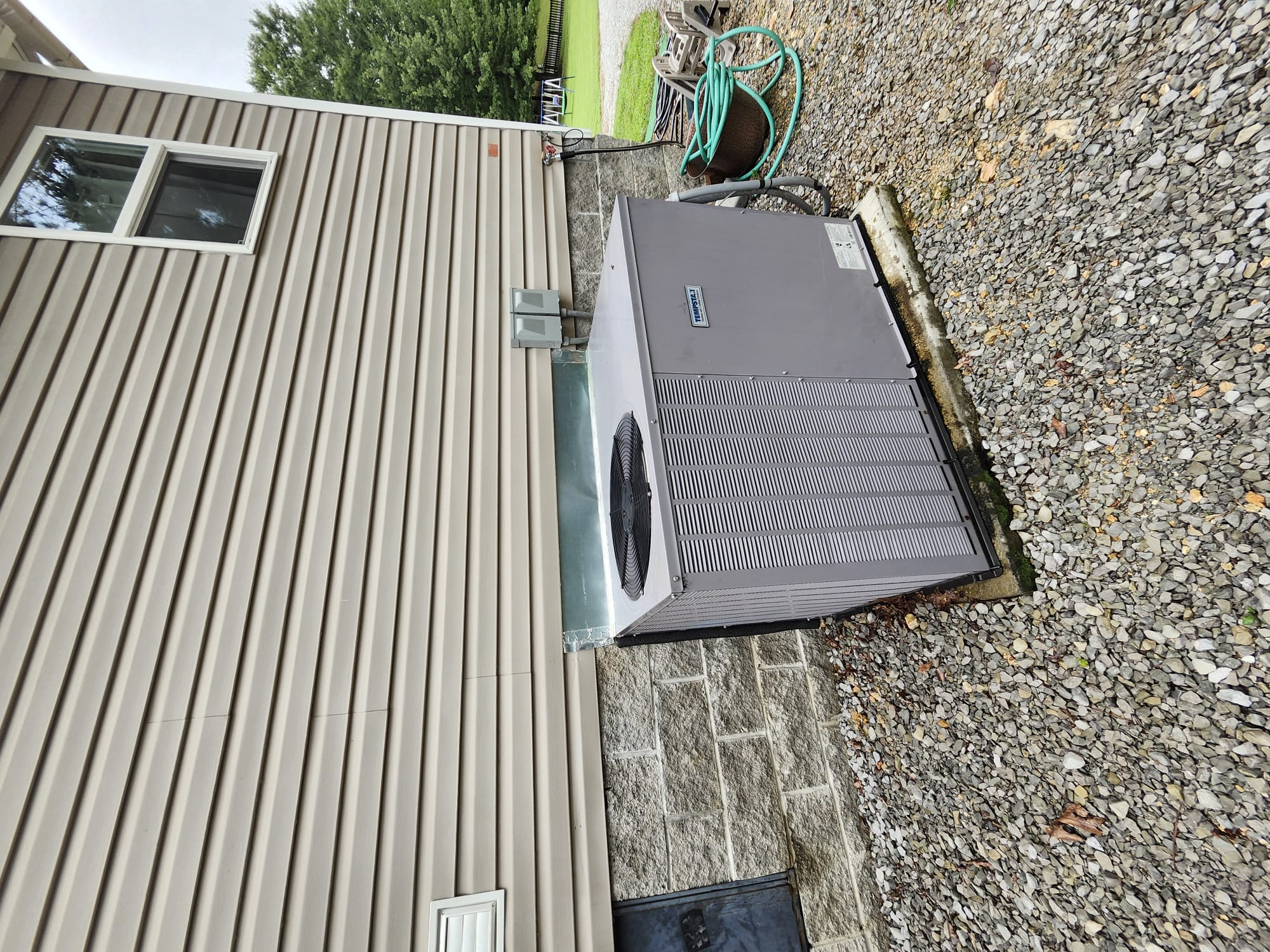 A clean outdoor HVAC unit installed beside a home