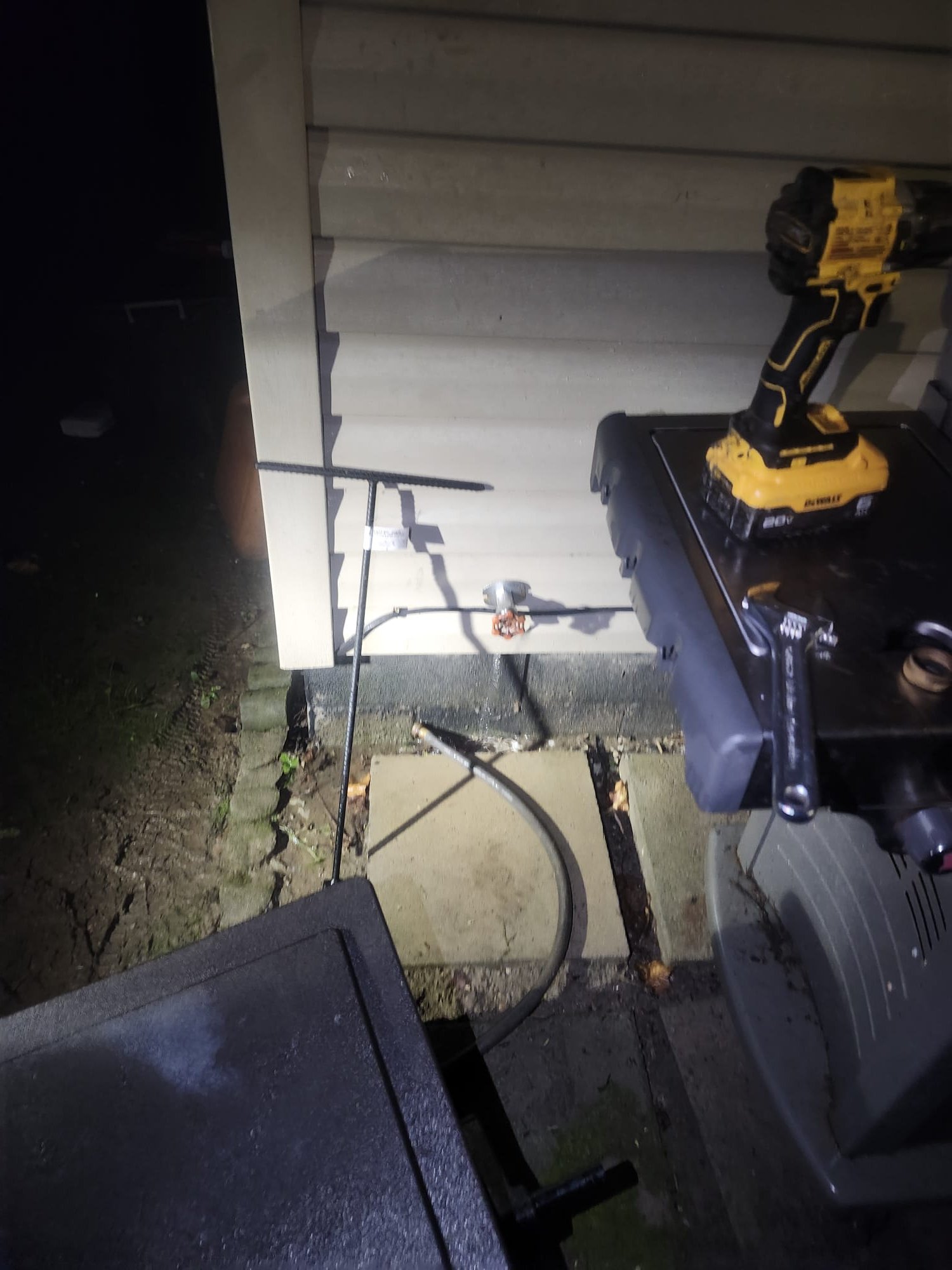 Outdoor faucet leaking beside a home at night