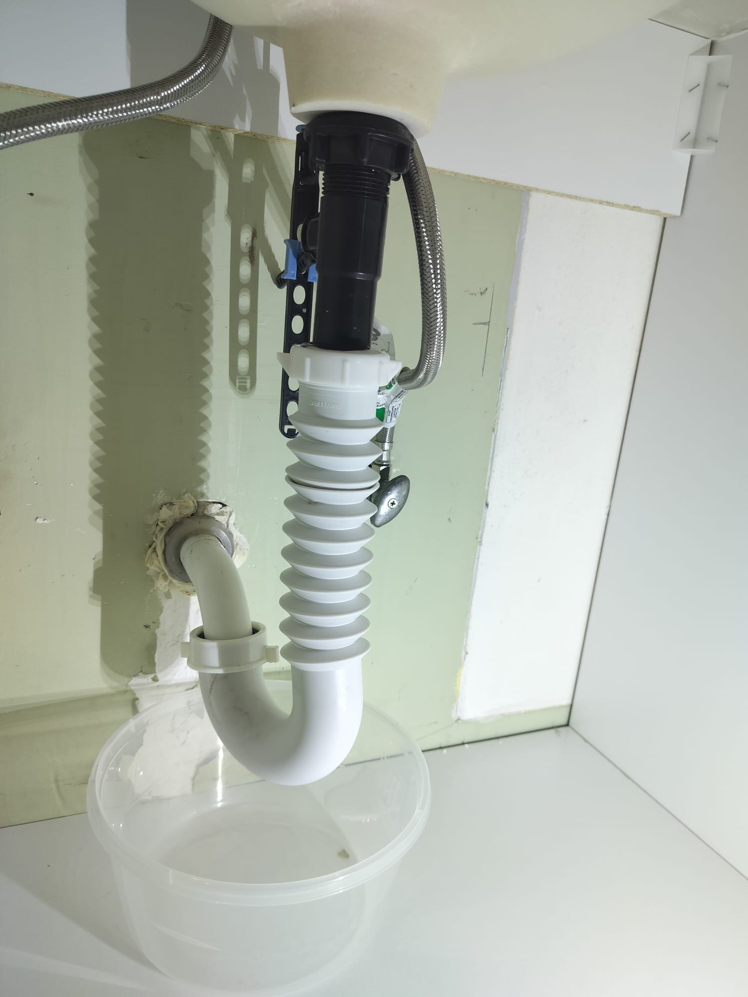 Plumbing work under a sink with a drain setup being checked
