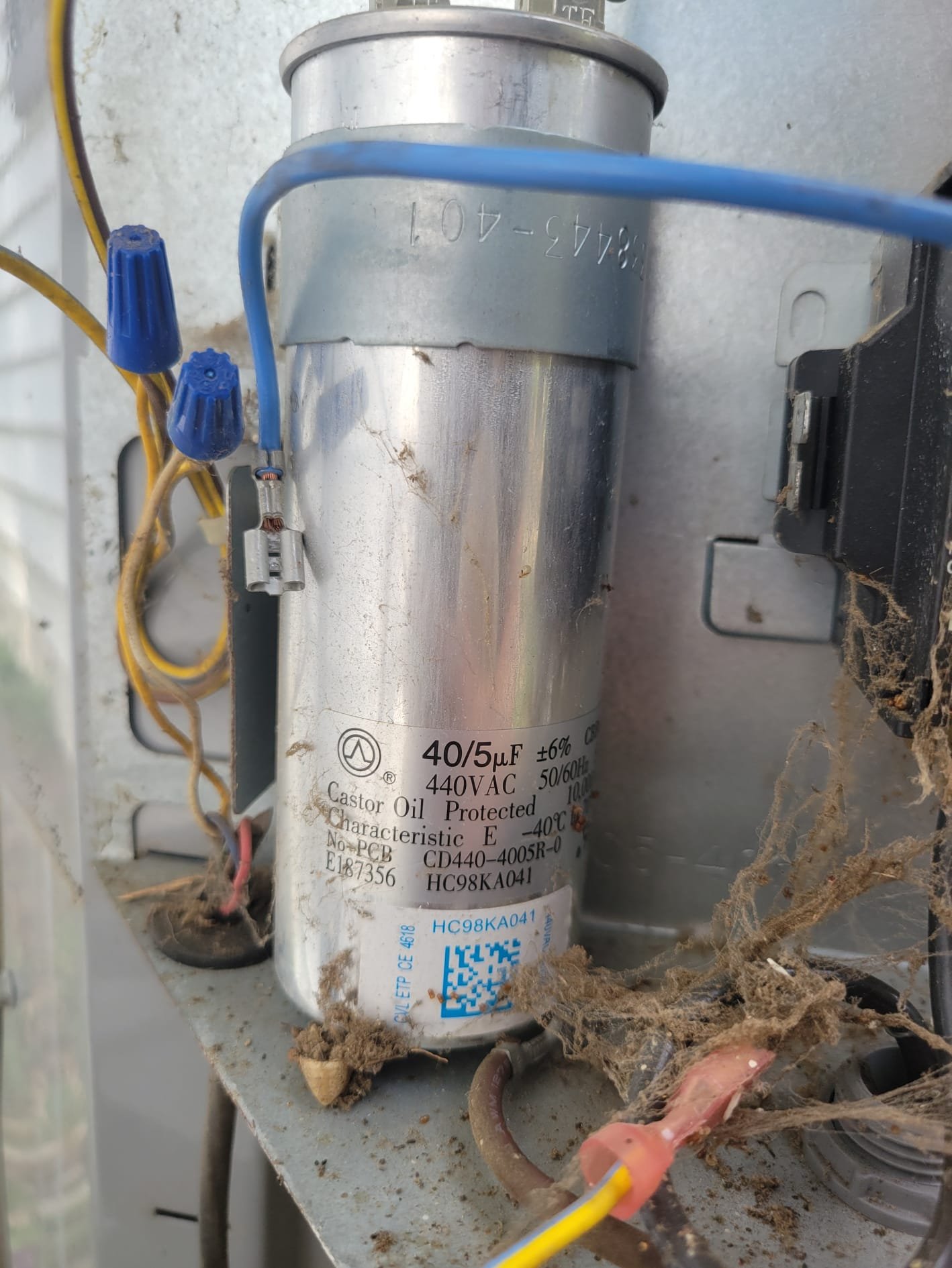 HVAC technician inspecting an older outdoor AC electrical compartment