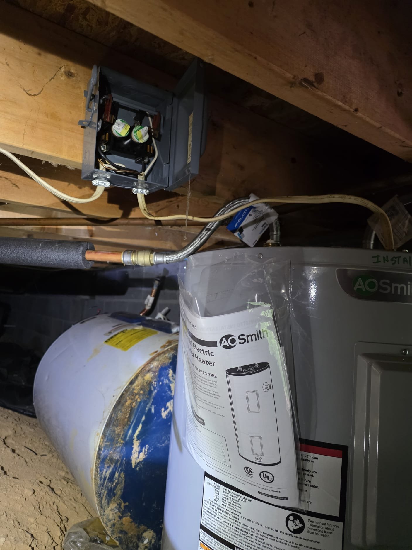 A newly installed electric water heater in a tight utility space