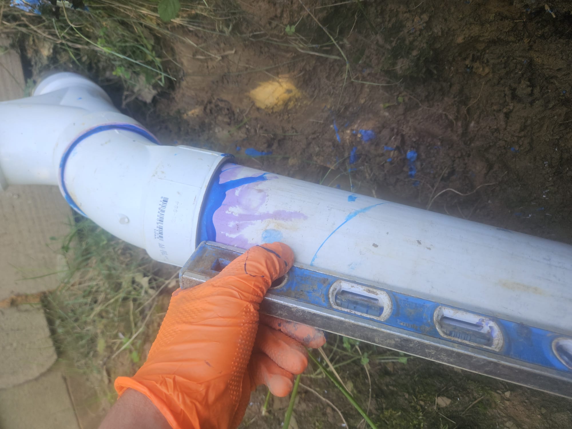 HEP technician checking pipe slope in a trench