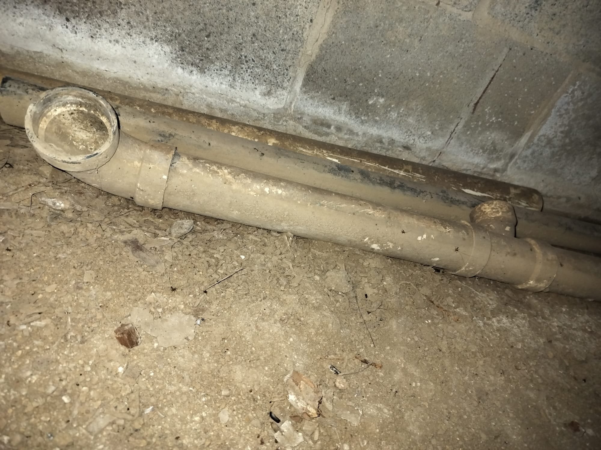 An older crawlspace drain area that shows why hidden plumbing should be checked carefully