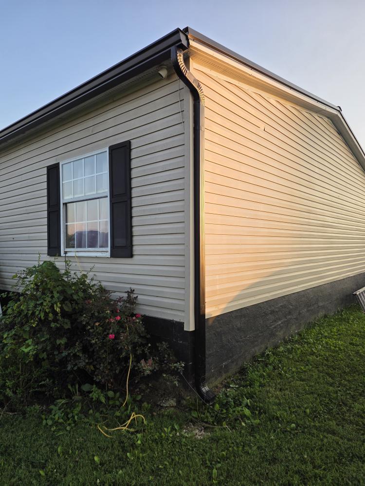 Clean black gutter and downspout running along the corner of a home exterior