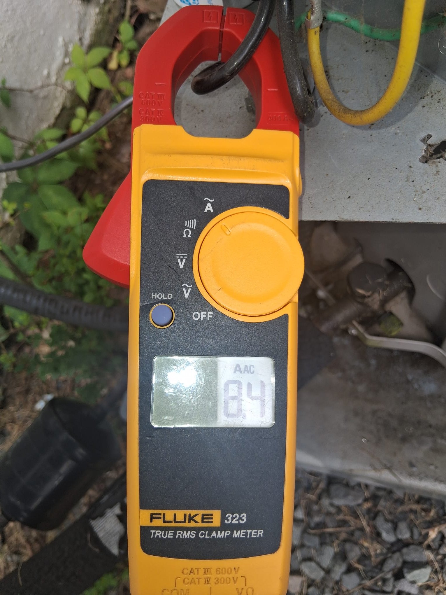 A technician using a clamp meter to check HVAC electrical operation
