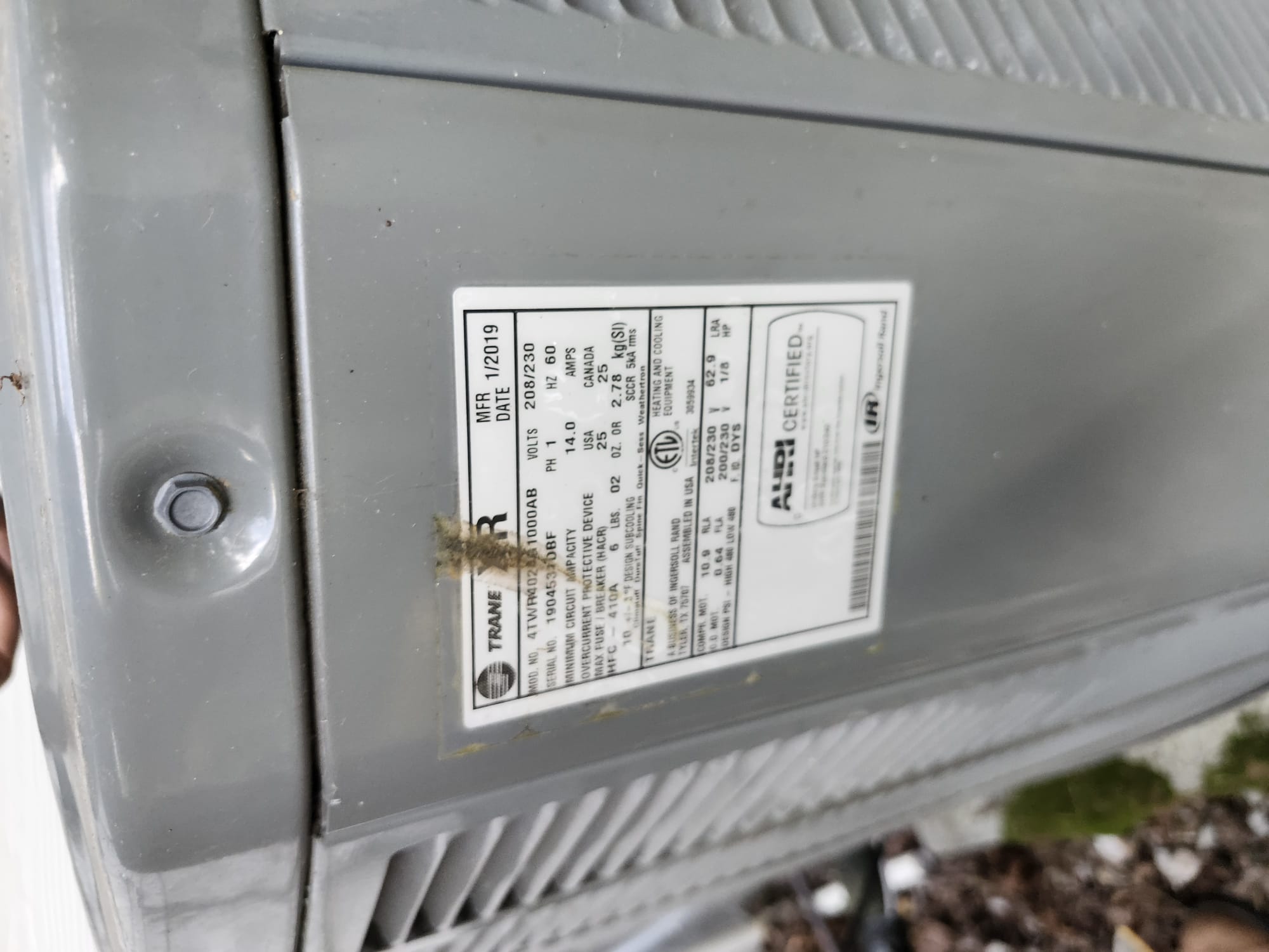 A technician checking the unit information label during HVAC service.