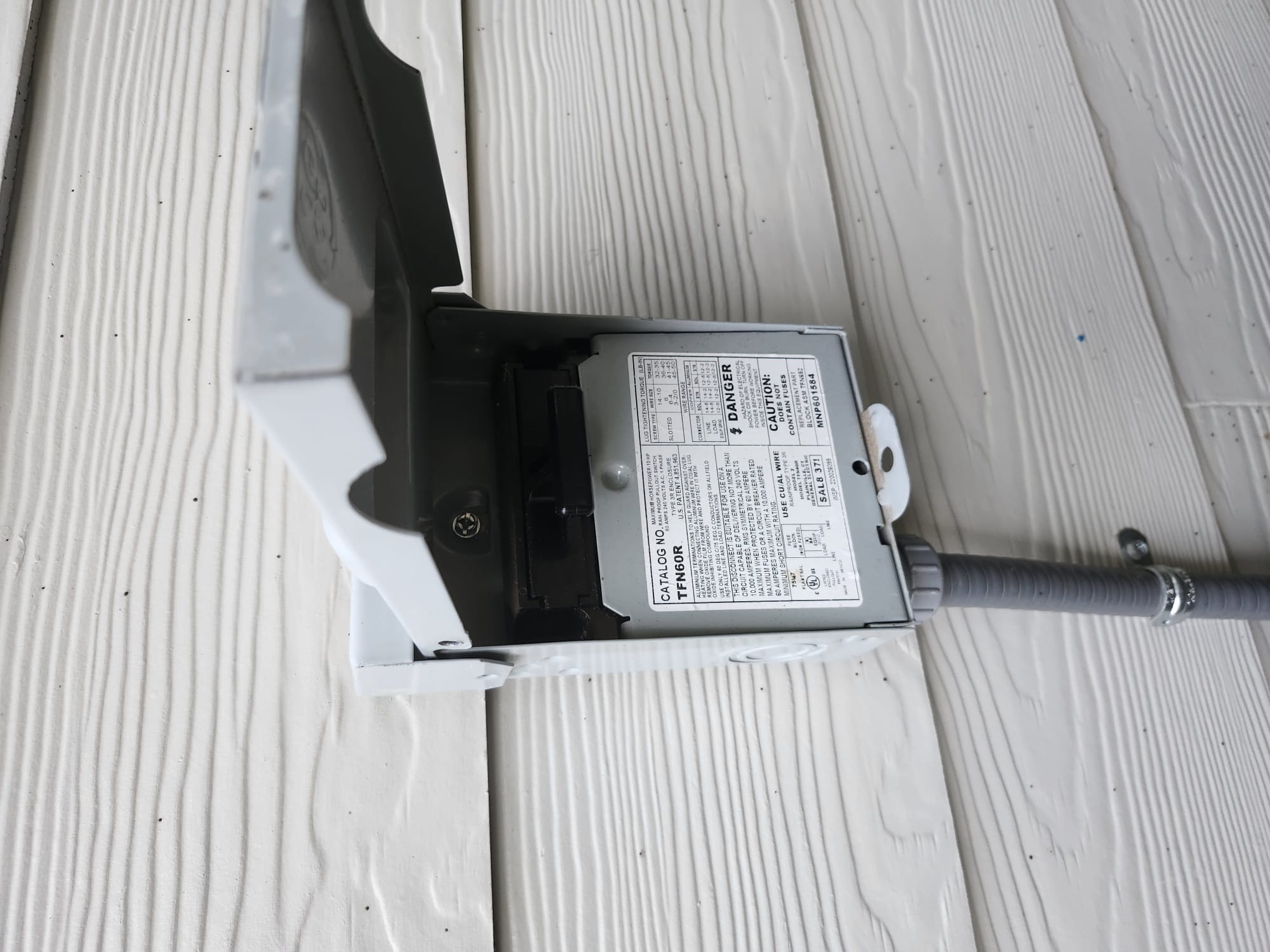 A clean outdoor electrical disconnect box mounted near the HVAC unit.