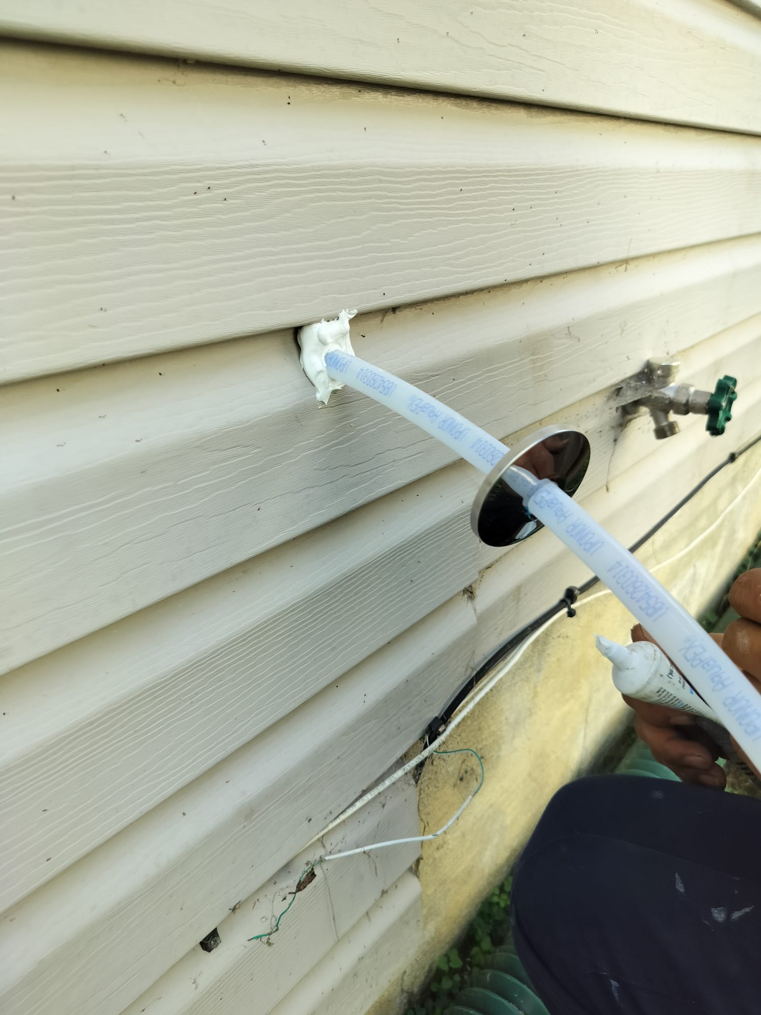 Exterior wall opening sealed around new plumbing pipe