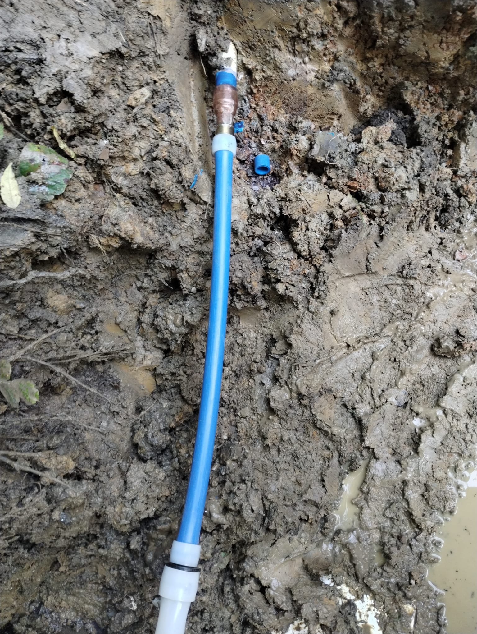 A fresh blue water line and new fittings installed in the trench